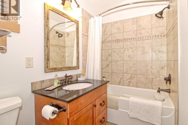 Bathroom with a vanity, granite countertop, bathtub, shower, and tiled walls. - 6931 Barcelona Drive Unit# 62, Kelowna