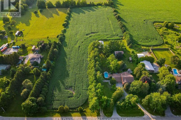 Aerial view of a rural property with a large cornfield, houses, and trees. - 6946 Fife Road, Guelph/eramosa