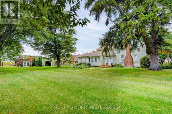 View of the house and yard from the side, showing trees and outbuildings. - 695 Cameron Road, Dawn Euphemia