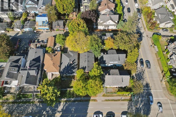 Overhead view of several houses with dark roofs and green trees lining the street. - 695 E 12th Avenue, Vancouver