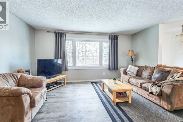 Bright living room featuring large window, two sofas, and wooden coffee table - 69565 Range Road 65, Grovedale
