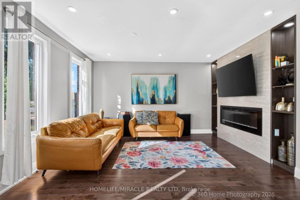 Living room with dark wood floors, a grey sectional sofa, and windows with curtains. - 696 Sheppard Avenue, Pickering