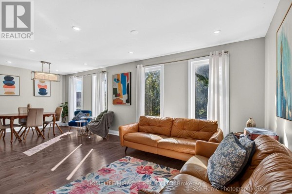 Living room with grey sectional sofa, ornate rug, and wall-mounted television above fireplace. - 696 Sheppard Avenue, Pickering