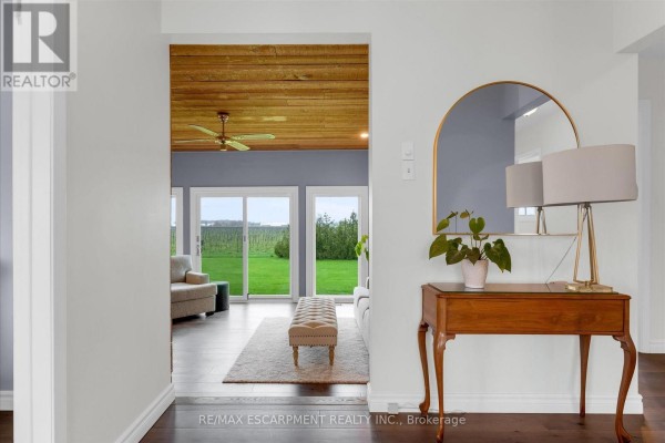 Dining room with a wood table, upholstered chairs, and a large window with black drapes. - 698 Concession 6 Road, Niagara On The Lake