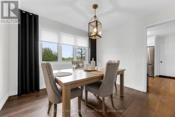 Dining room with wood table, upholstered chairs, buffet, and artwork on the wall. - 698 Concession 6 Road, Niagara On The Lake