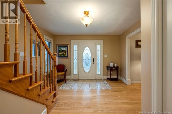 Interior front entrance foyer with a staircase, tiled floor, and double glass front doors. - 698 Frampton, Moncton