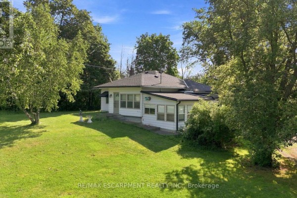 Exterior view of the garage door and side of the house with brick and beige siding, and a paved driveway. - 698 York Road, Hamilton