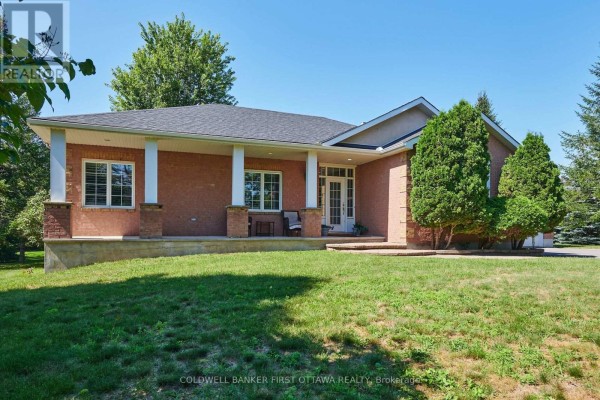 Side view of the red brick bungalow's front entrance with a covered porch and seating. - 6983 Lakes Park Drive, Ottawa
