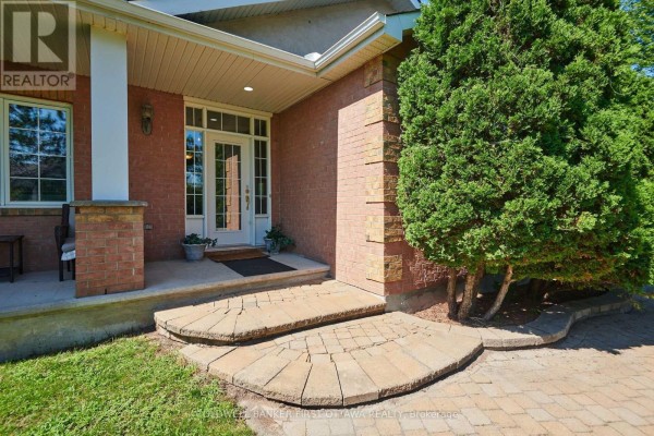 Close-up of the front entrance steps and glass double doors of the red brick bungalow. - 6983 Lakes Park Drive, Ottawa