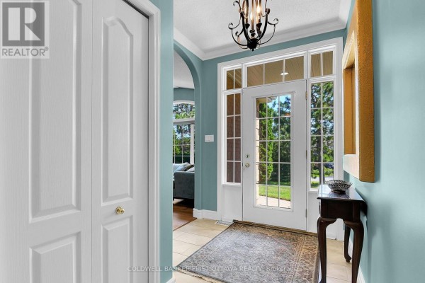 Interior entryway with tiled floor, pale blue walls, a large closet, and a glass-paned door. - 6983 Lakes Park Drive, Ottawa