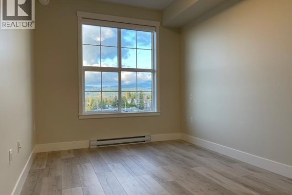 Room with beige walls, wood-look flooring, and a view of trees and sky. - 6xx 22638 119 Ave, Maple Ridge