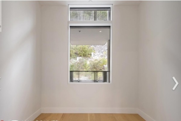 Minimalist white room with light wood floors and a large window with a roller blind. - 6xx 6687 Nelson Avenue, West Vancouver