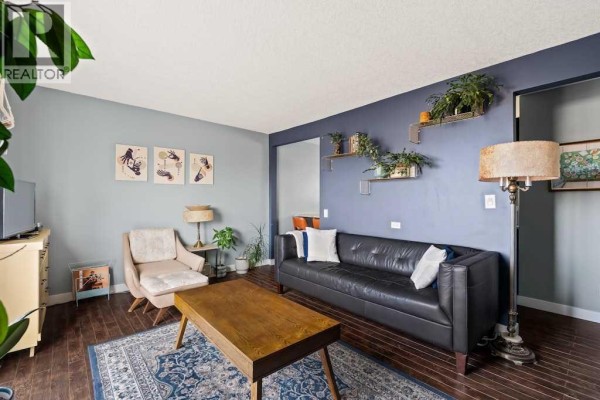 Living room and staircase with open railing, black leather sofa, and view to balcony. - 7, 1603 Mcgonigal Drive Ne, Calgary