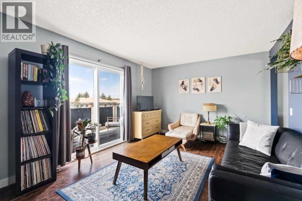 Balcony with outdoor seating and table, overlooking rooftops and trees under a cloudy sky. - 7, 1603 Mcgonigal Drive Ne, Calgary