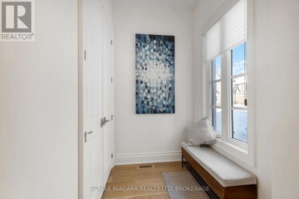 Entryway with white walls, bench seating, and abstract blue wall art. - 7 - 15 Arbourvale Common Road, St  Catharines