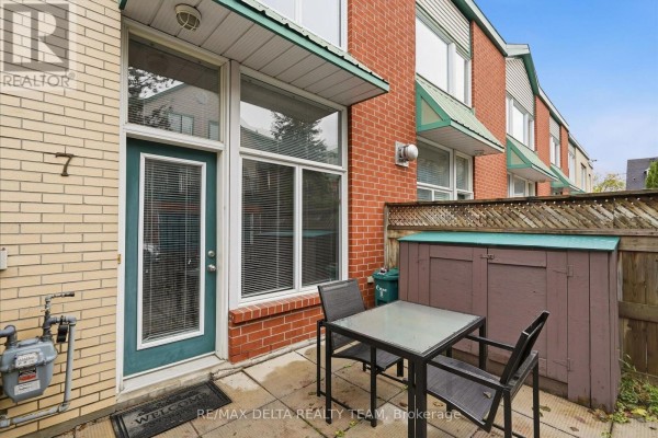 Front entrance of townhouse unit 7 with glass door, large windows, and small patio table. - 7 - 170 Cathcart Street, Ottawa