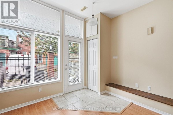 Interior dining area with large windows, tiled floor, and a built-in wooden bench. - 7 - 170 Cathcart Street, Ottawa