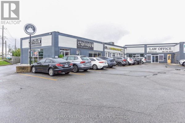 Exterior view of a commercial strip mall with parked cars and signage. - 7 - 1780 Albion Road, Toronto