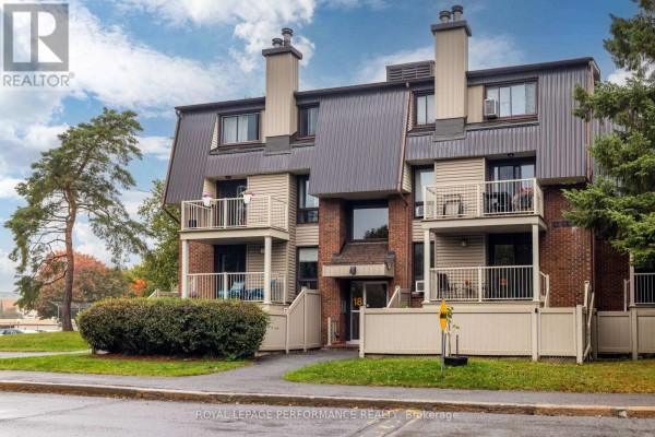 Exterior of an apartment building with mature trees and fall foliage. - 7 - 18 Sweetbriar Circle, Ottawa