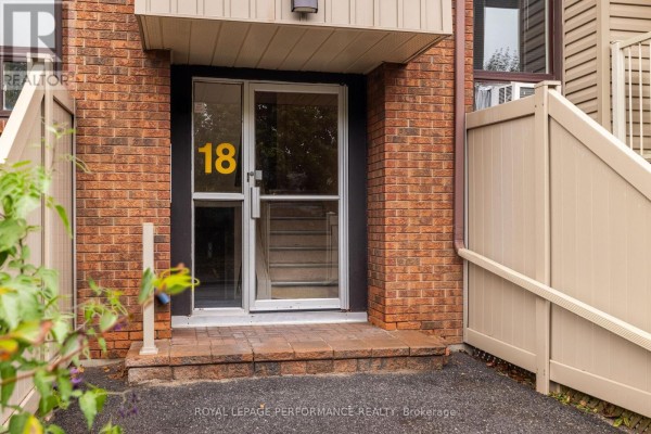 Close-up of the main entrance to apartment building 18, with glass doors and brick facade. - 7 - 18 Sweetbriar Circle, Ottawa
