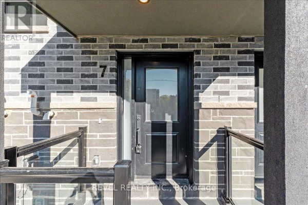 Front door of townhouse unit 7, featuring a black door with a glass pane. - 7 - 200 Railway Engine House Way, Whitby