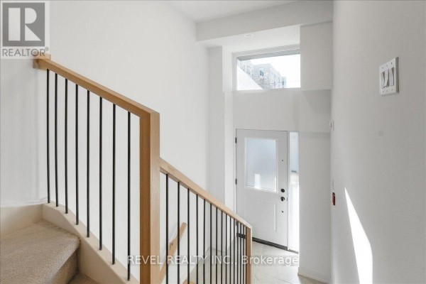 Interior view of a bright entryway with a staircase and a frosted glass door. - 7 - 200 Railway Engine House Way, Whitby