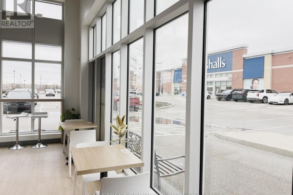 View from inside a commercial space looking out through large windows at a parking lot and Marshalls store. - 7 - 3101 Appleby Line, Burlington
