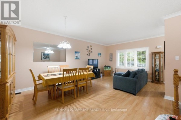 Dining room with a large table and chairs, connected to a living area with a sofa. - 7 - 34 Southbrook Drive, Hamilton