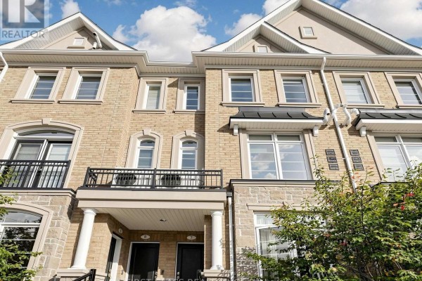 Close-up exterior view of a beige brick townhouse with stone accents and balconies. - 7 - 37 Drewry Avenue, Toronto