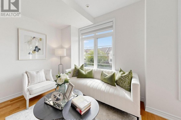 Living room with white sofas, wood floors, two dark oval coffee tables, and artwork on white walls. - 7 - 37 Drewry Avenue, Toronto