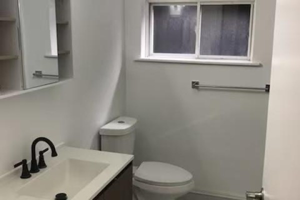 Bathroom with white walls, a vanity with a black faucet, toilet, and a frosted sliding window. - 7 - 373 Broadview Avenue, Toronto