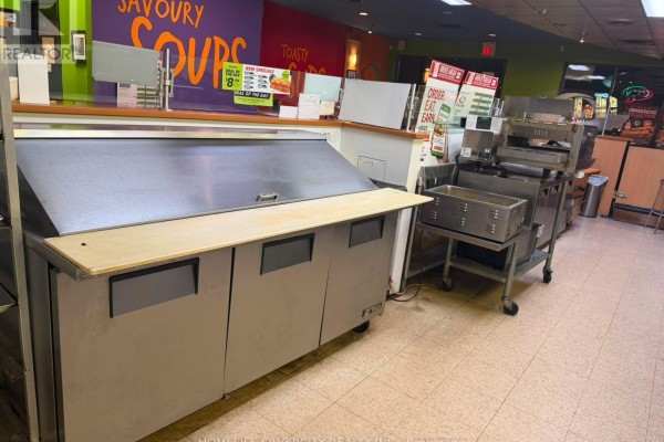 Stainless steel deli display case and food preparation equipment in a commercial kitchen. - 7 - 3969 Montrose Road, Niagara Falls
