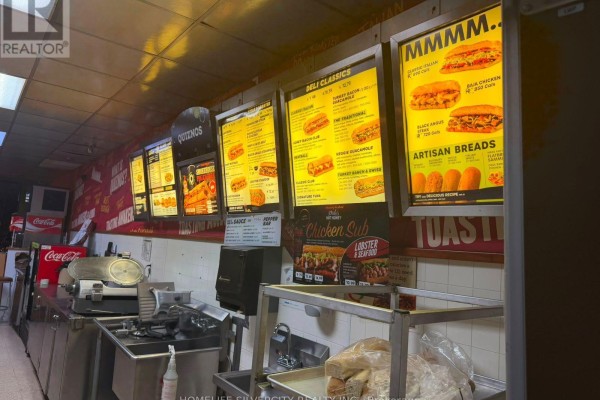 Menu boards above a counter with food images, including subs and artisan breads. - 7 - 3969 Montrose Road, Niagara Falls