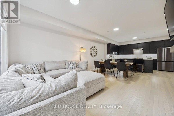 Open concept living and dining area with a sectional sofa and modern kitchen. - 7 - 40 Baynes Way, Bradford West Gwillimbury