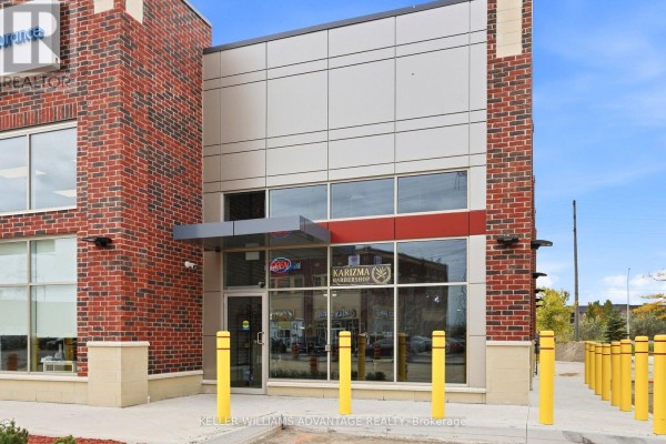 Close-up of commercial storefronts with glass doors and windows, featuring yellow bollards and red brick details. - 7 - 41 James Snow Pkwy N Parkway, Milton