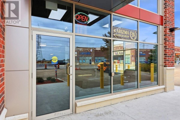 Entrance to a barbershop with glass doors, a sign that says "Open", and reflections of the parking lot. - 7 - 41 James Snow Pkwy N Parkway, Milton