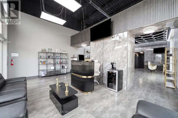 Reception area with black leather sofas, a modern reception desk with gold accents, and shelves of products. - 7 - 41 James Snow Pkwy N Parkway, Milton
