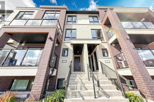 Front exterior of a townhouse with a long staircase and dark grey front door. - 7 - 45 Romilly Avenue, Brampton