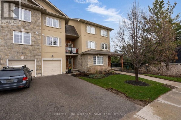 Front exterior of a townhouse complex with beige and stone accents, grassy lawn, driveway, and mature trees. - 7 - 49 Ferndale Drive S, Barrie