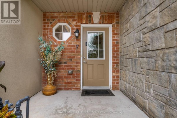 Entrance to unit 7 featuring a tan door with a glass insert, brick and stone exterior walls, and potted plants. - 7 - 49 Ferndale Drive S, Barrie