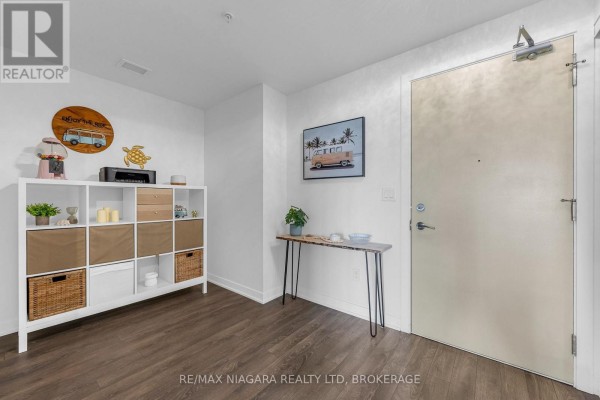 Apartment entryway with white shelving unit, console table, and beige door. - 1307 - 550 North Service Road, Grimsby