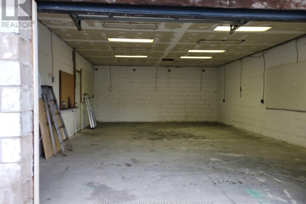 Interior of an empty garage with concrete floor, cinder block walls, and fluorescent lighting. - 7 - 6029 Old Scugog Road, Clarington
