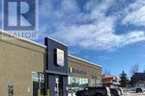 Commercial building exterior with tan siding and a dark blue entrance under a bright sky. - 7 - 649 Yonge Street, Barrie