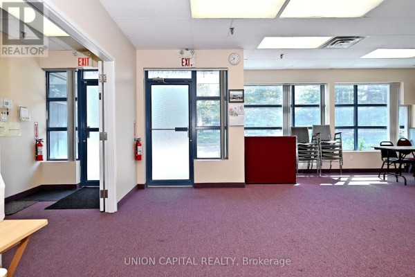 Interior view of a room with purple carpet, chairs, tables, and exit signs. - 7 & 8 - 95 Royal Crest Court, Markham