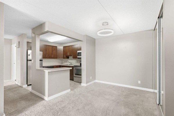 Open concept living area connected to a kitchen with dark wood cabinets. - 7 134 Regis Drive, Winnipeg