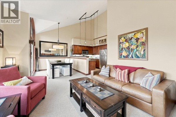 Living and dining area with vaulted ceilings, kitchen, and a large mirror. - 7 2323 Taluswood Place, Whistler