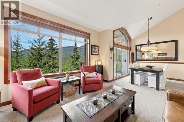 Living area with fireplace, dining table, and panoramic mountain and forest views. - 7 2323 Taluswood Place, Whistler