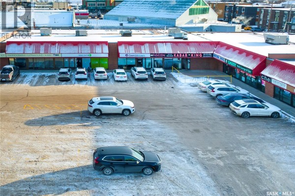 Aerial view of a commercial strip mall with multiple businesses and a parking lot with cars. - 7 3110 8th Street, Saskatoon
