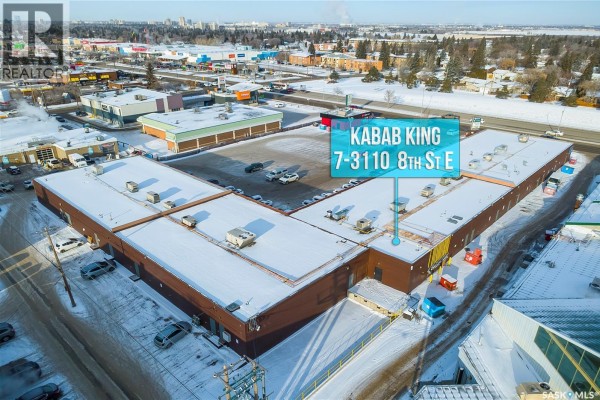 Aerial view of a large, L-shaped commercial building complex covered in snow. - 7 3110 8th Street, Saskatoon