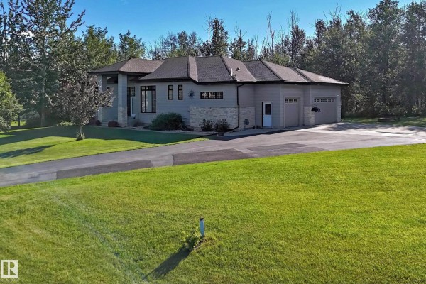 Side view of a grey house with a large driveway and attached three-car garage. - #7 53216 Rge Road 264, Rural Parkland County